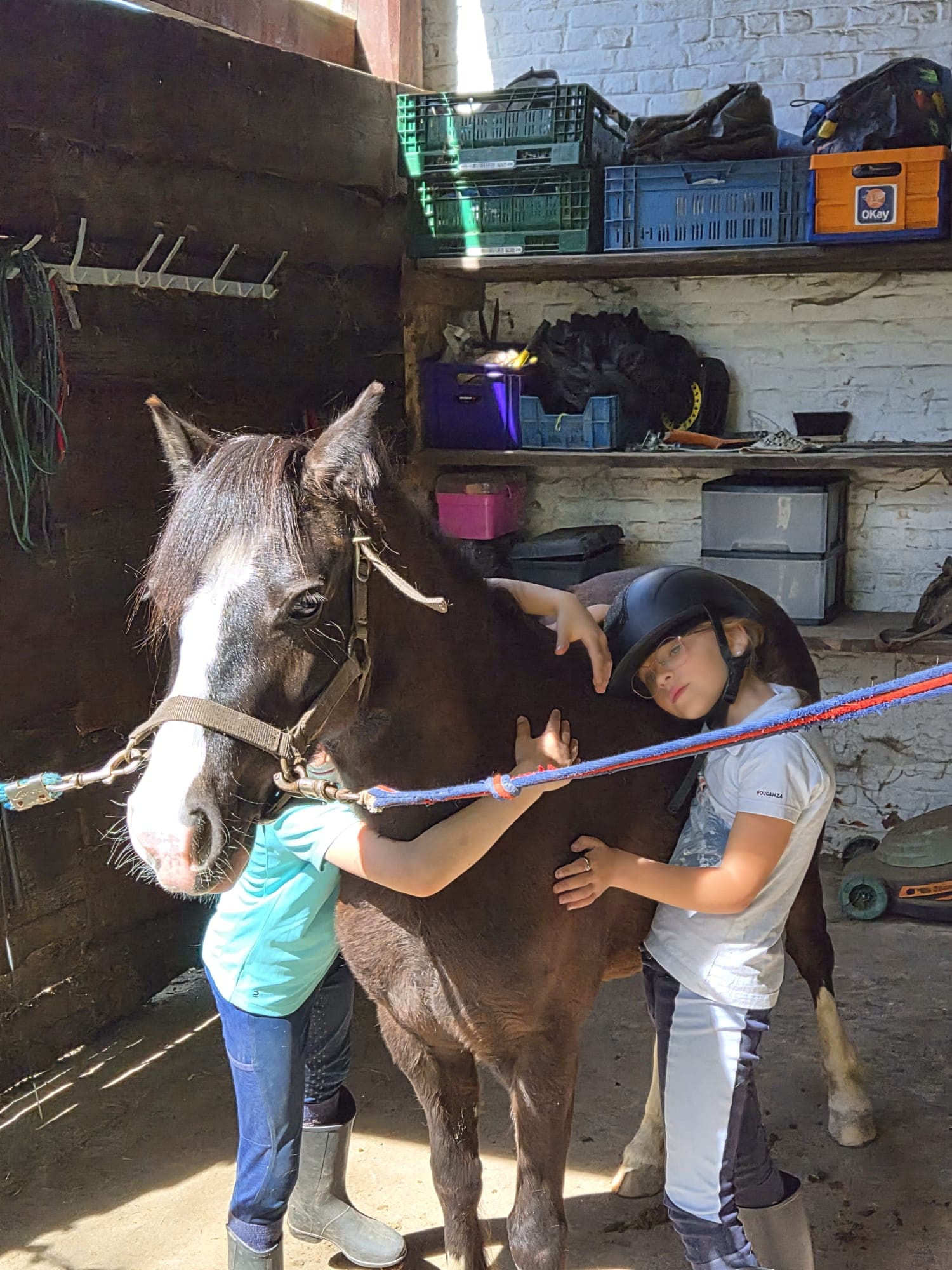 Enfants qui câlinent un poney en écurie